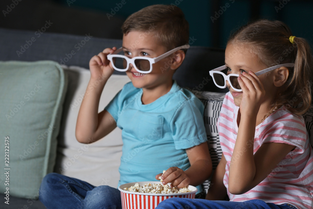 Children eating popcorn while watching TV in evening