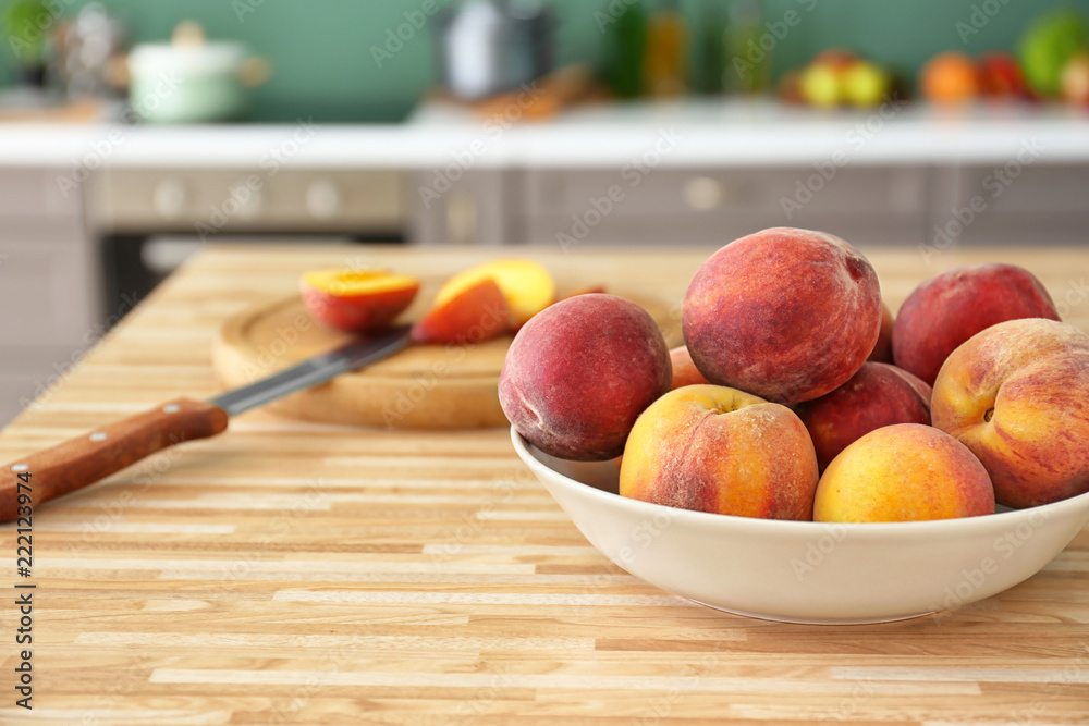 Bowl with fresh peaches on wooden table