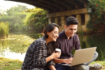 Wall Mural - Happy asian couple sitting and surfing the net together