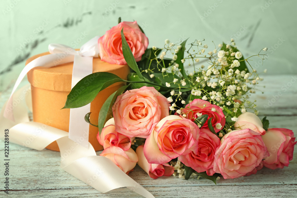 Beautiful roses with gift box on wooden table