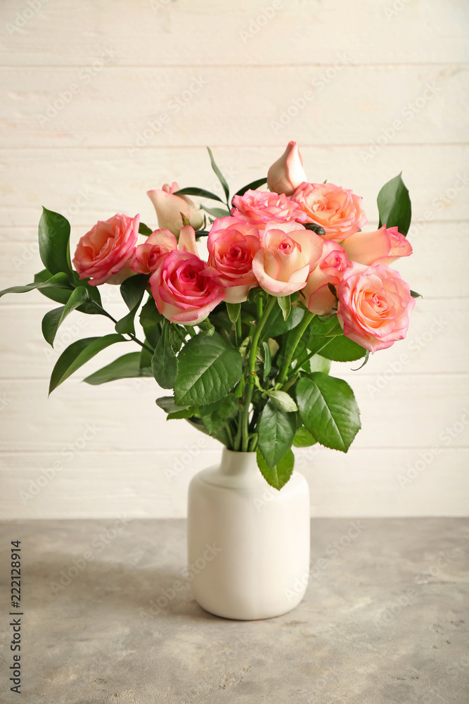 Vase with beautiful roses on grey table