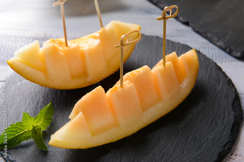 Sliced ripe melon on slate plate