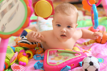 Wall Mural - Cute little baby with toys lying on bed