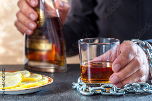 Fotografie, Obraz Hand of male chained to glass of alcohol drink