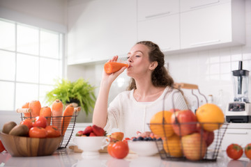 Healthy young woman in a kitchen with fruits and vegetables and juice