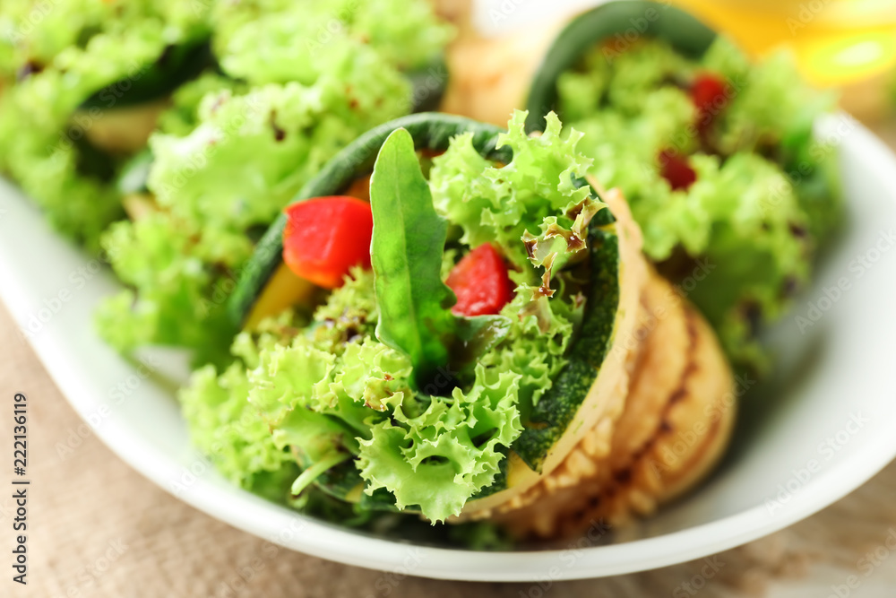 Tasty zucchini rolls with lettuce on plate, closeup