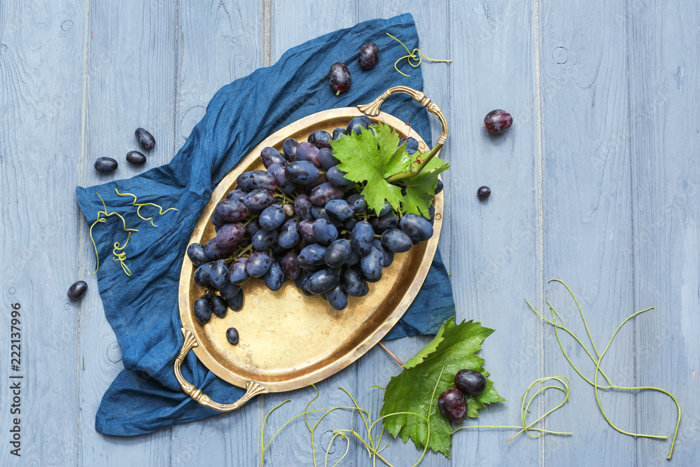 Tray with fresh ripe grapes on wooden table