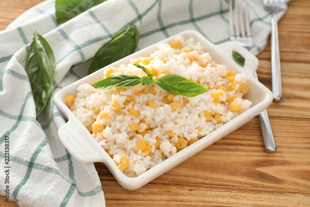 Dish with tasty boiled rice and corn kernels on wooden table