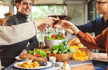 Group of young people celebrating Christmas party dinner with clinking glass of wine and selfie