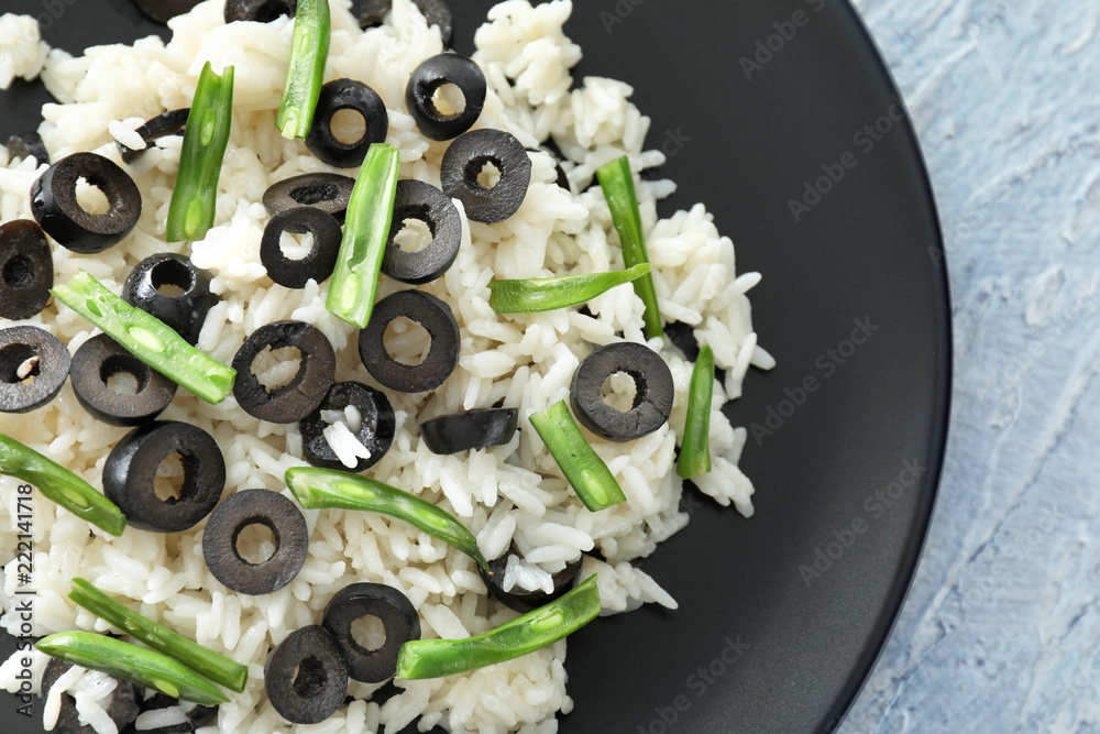 Plate with tasty boiled rice, olives and green beans on light table, closeup