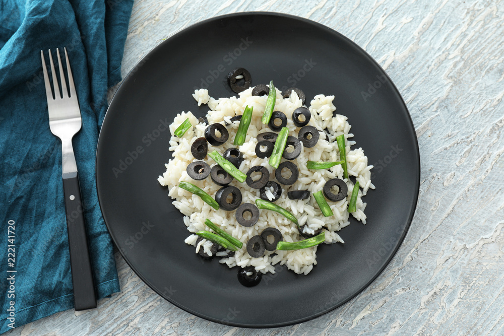 Plate with tasty boiled rice, olives and green beans on light table