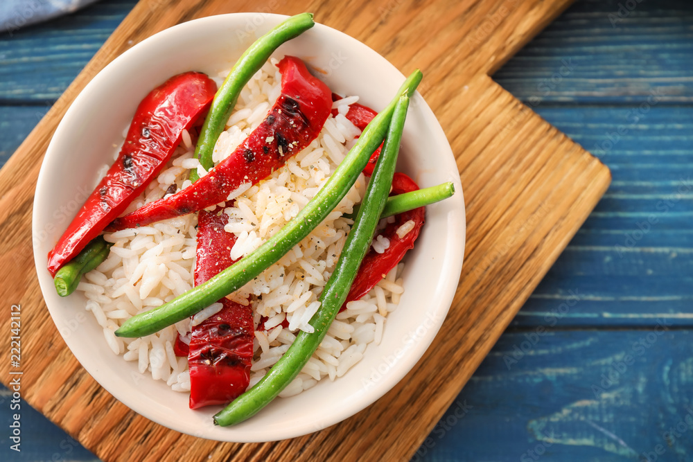 Plate with tasty boiled rice and vegetables on wooden table