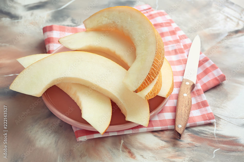 Plate with slices of ripe melon on color table