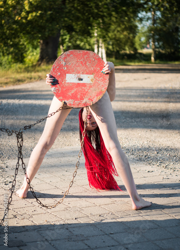 Fotomural Nude beautiful woman holding STOP road sign and covering herself outdoors
