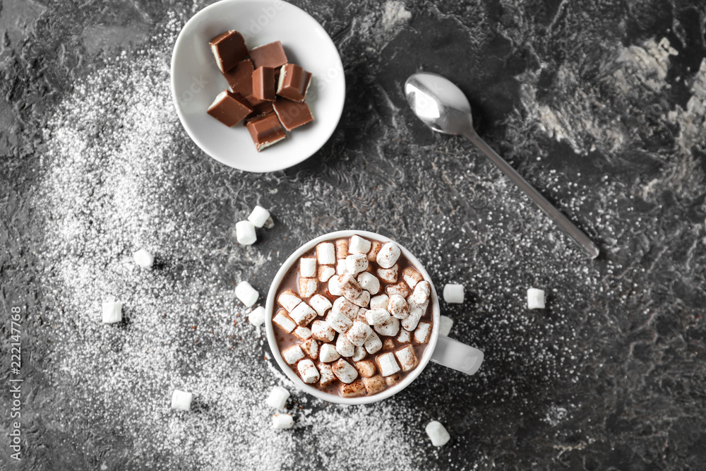 Cup of delicious cocoa with marshmallows and chocolate on grunge table