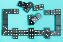 Black Old, Vintage Dominoes On A  Cardboard Turquoise Background. The Concept Of The Game Dominoes. Selective Focus