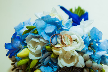 Wedding ring. Two gold romantic rings of the bride and groom are on a bouquet of blue and blue flowers