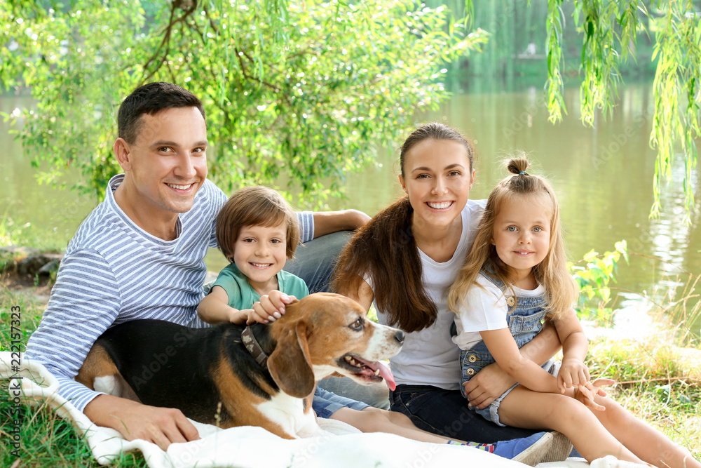 Happy family with cute dog resting in park