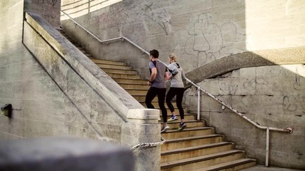 Wall Mural - Young couple runners running up the stairs in the city.