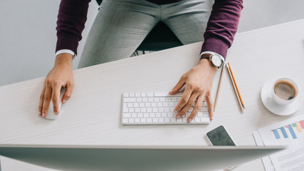 cropped image of designer working at table with computer in office