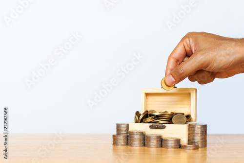 Hand Putting Money Coins In Wood Box And Coins Stack On White Wall - hand putting money coins in wood box and coins stack on white wall background investment and saving concept
