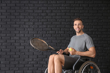 Poster - Young tennis player sitting in wheelchair against dark brick wall