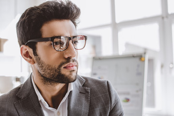 Wall Mural - portrait of handsome businessman in glasses looking away in office