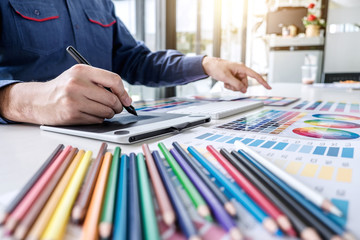 Poster - Image of male creative graphic designer working on color selection and drawing on graphics tablet at workplace with work tools and accessories