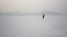 Dramatic Aerial Of Young Boy Running In Utah Desert Salt Flat