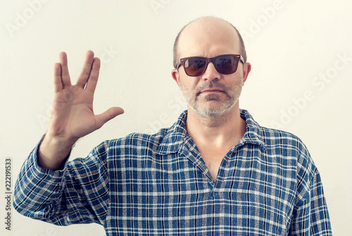 Fotomural Portrait of an adult man with a gray beard, dark glasses shirt showing a gesture