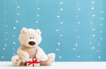 Wall Mural - A teddy bear and gift box on a shiny light blue background