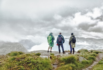 three male person looking away standing at the edge of cliff over canyon in norway. hiking concept. 