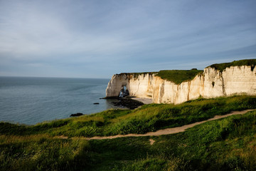 Magnificent sunset view of Etretat cliffs, lit by the last rays of the sun. Famous coastline of Cote d'Albatre in Normandy, France, Europe.