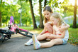 © MNStudio - Adorable girl comforting her little sister after she fell off her bike at summer park. Child getting hurt while riding a bicycle.