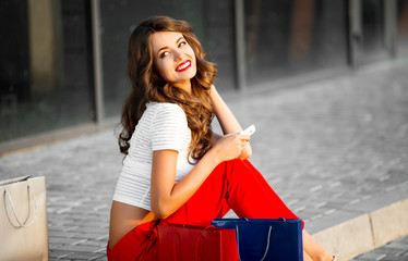 Wall Mural - Young woman with shopping bags resting near shop