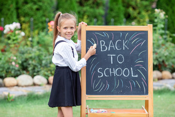 Happy little schoolgirl with a chalkboard outdoor