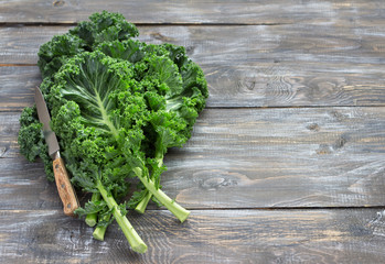 Wall Mural - Fresh green curly kale leaves on a cutting board on a wooden table. selective focus. free space. rustic style. healthy vegetarian food