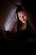 © Aleksei Lazukov - young woman reading a book under the covers and smile