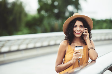 Wall Mural - Portrait of attractive young woman in straw hat drinking coffee and calling on phone