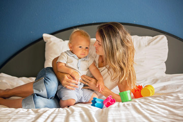 Poster - Mother and baby boy, cute child, playing together in bed with toy