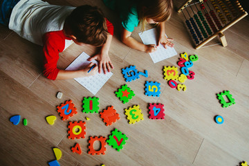 Wall Mural - little boy and girl learn to write and calculate numbers