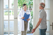 © DragonImages - Elderly man opening door to smiling doctor making visit at home