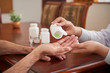 © DragonImages - Crop shot of doctor putting pills in hand of senior man sitting at table