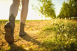 View on legs and shoes of walking girl in the green orchard by the path, during sunny day.