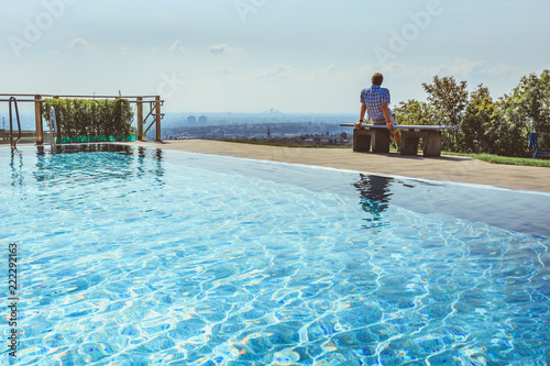 Zdjęcie XXL Obsługuje obsiadanie na ławce blisko plenerowego pływackiego basenu cieszy się pięknego widok nad miastem