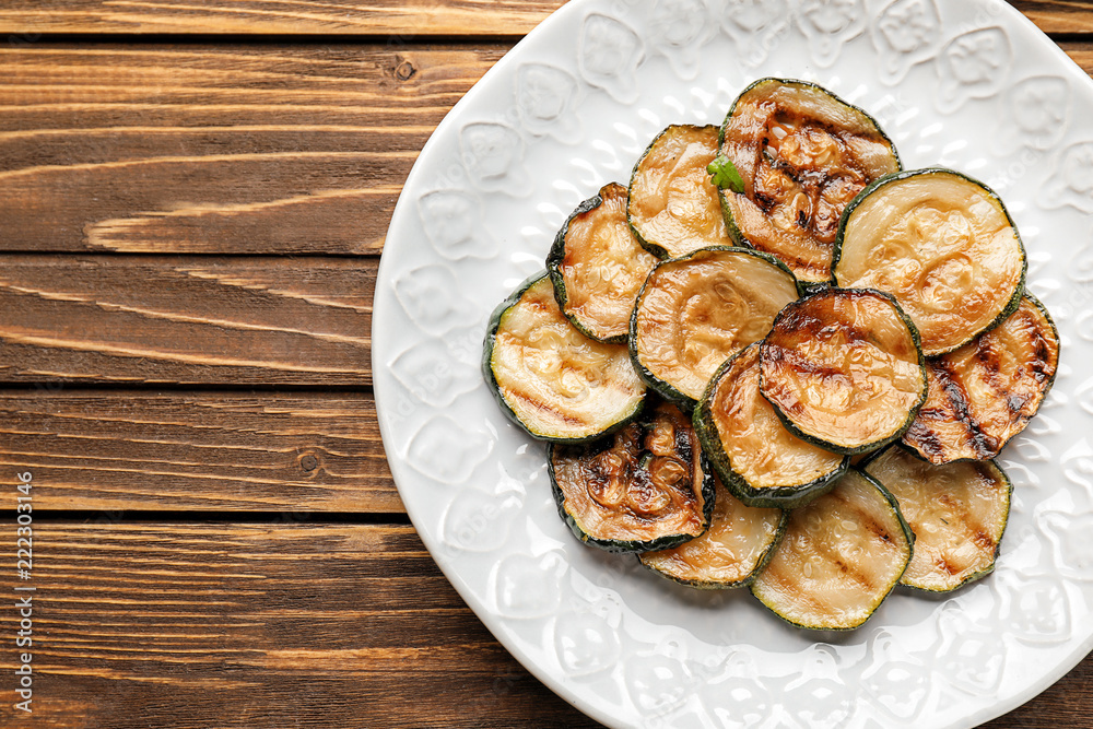 Plate with tasty grilled zucchini on wooden table