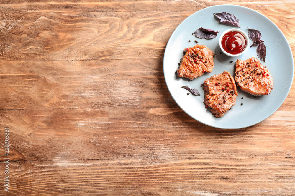 Plate with delicious grilled steak and sauce on wooden table