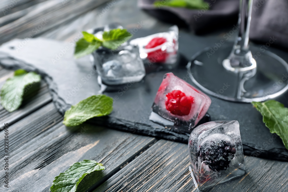 Ice cubes with frozen berries on table
