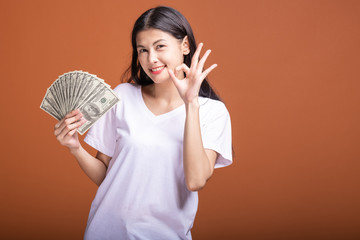 Wall Mural - Woman holding cash notes isolated in orange background.