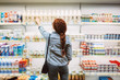 Young woman in striped shirt from back choosing dairy products in supermarket
